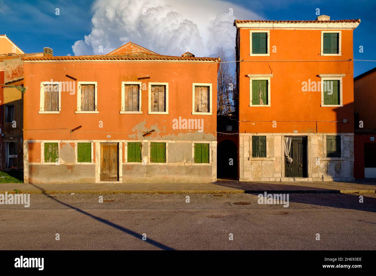 Molte finestre in due vecchie case arancioni con persiane chiuse, isola di Pellestrina, laguna veneta, Italia Foto Stock
