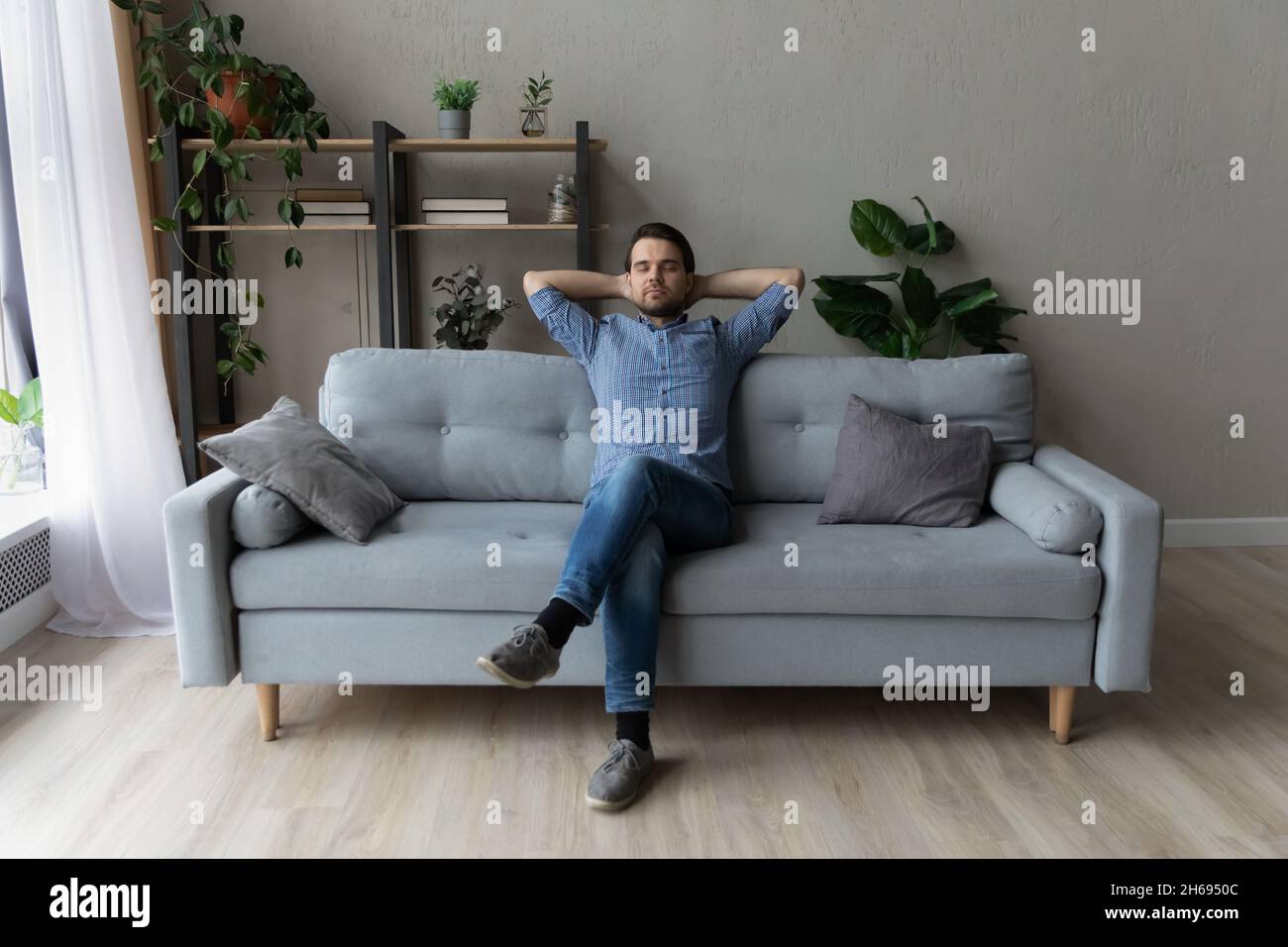 Felice spensierato uomo millenario napping su un comodo divano. Foto Stock