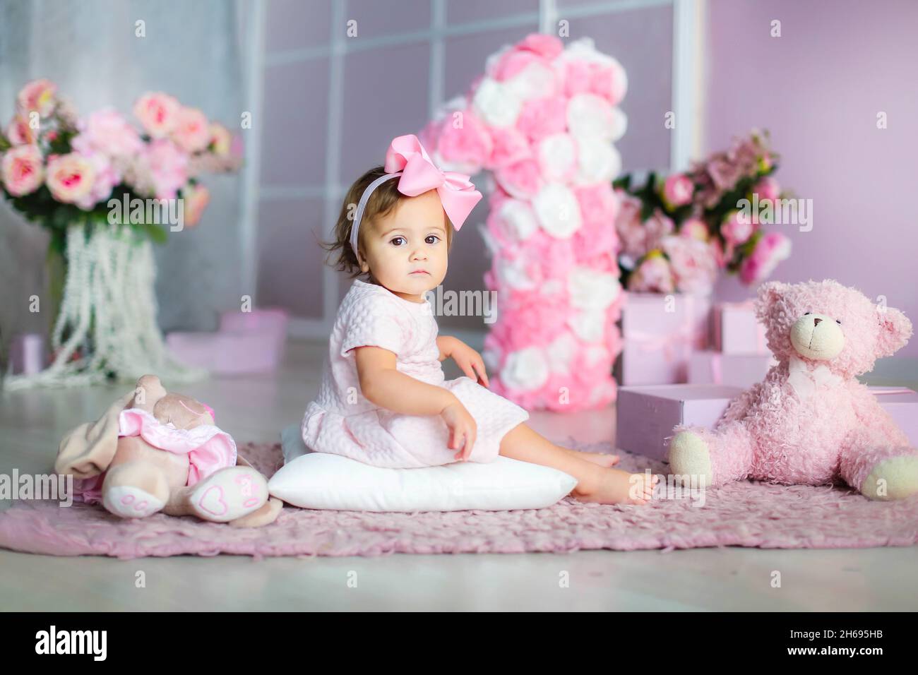 Ragazza bambino 1 anno di vita su uno sfondo di paesaggio rosa grandi numeri 1. Foto Stock