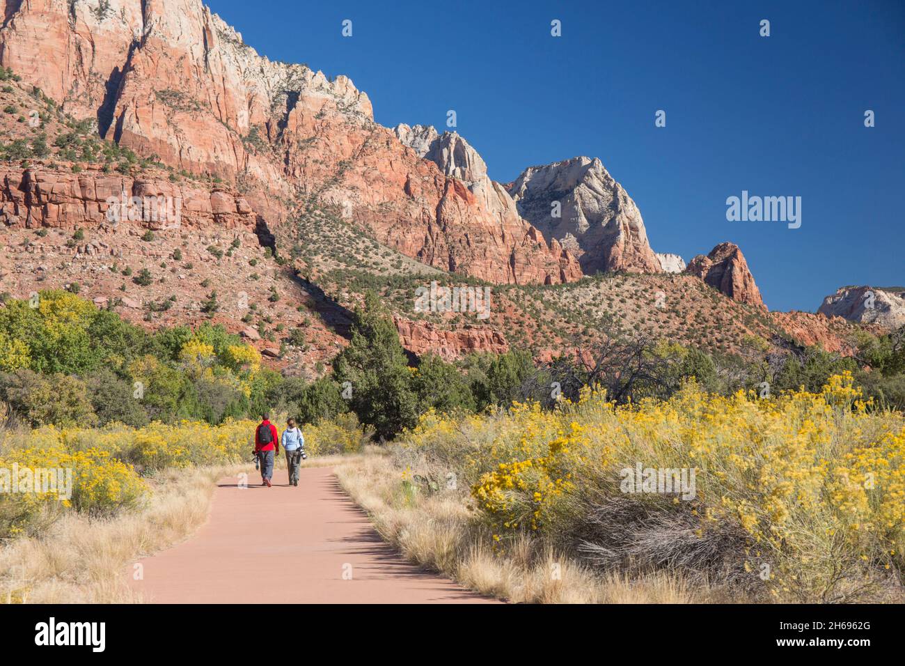 Zion National Park, Utah, USA. Due fotografi che si dirigono verso nord lungo il sentiero Pa'rus verso Sentinel e Jacob Peak, in autunno. Foto Stock