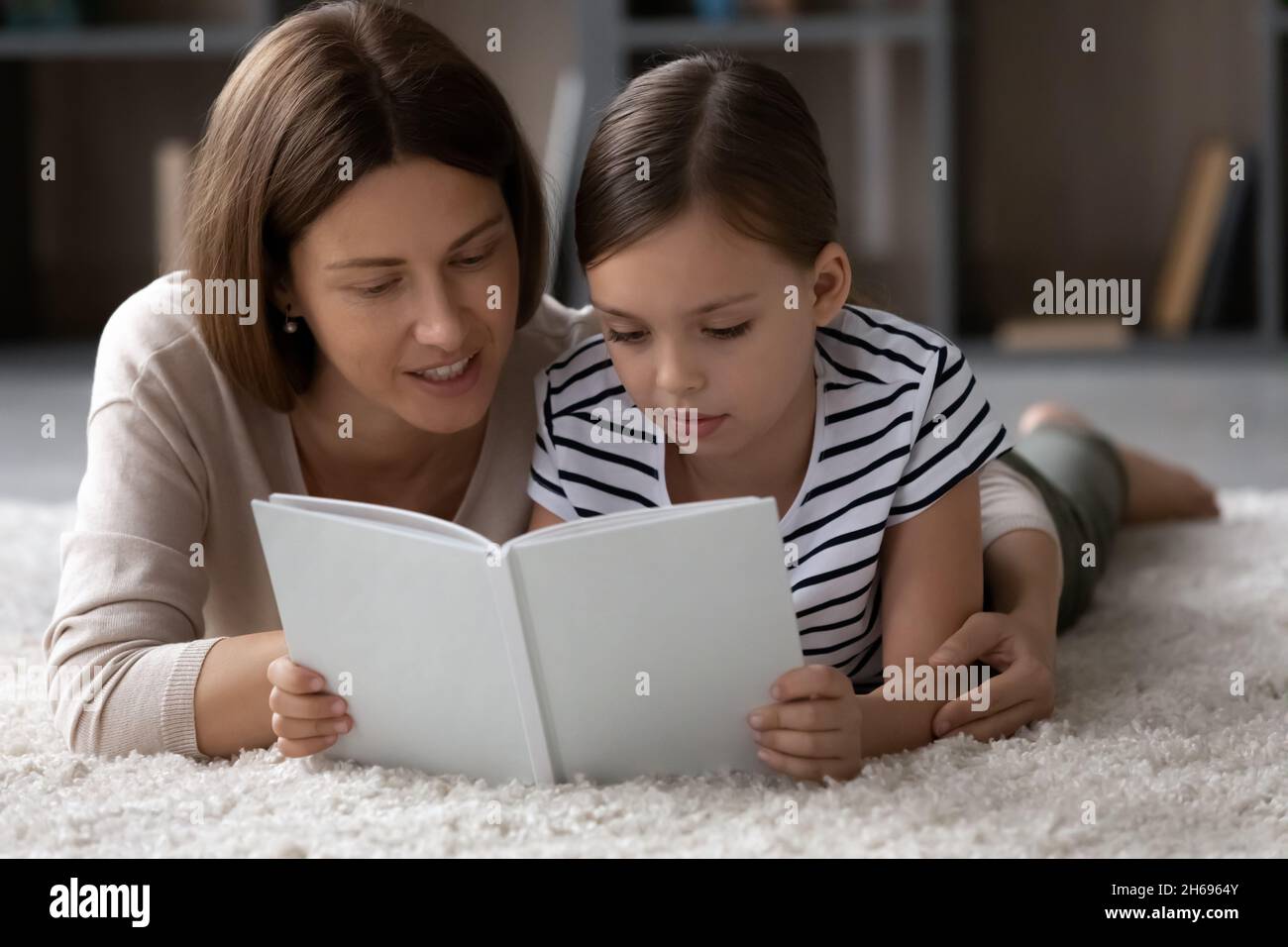 Primo piano su madre sorridente con la bambina che legge libro insieme Foto Stock