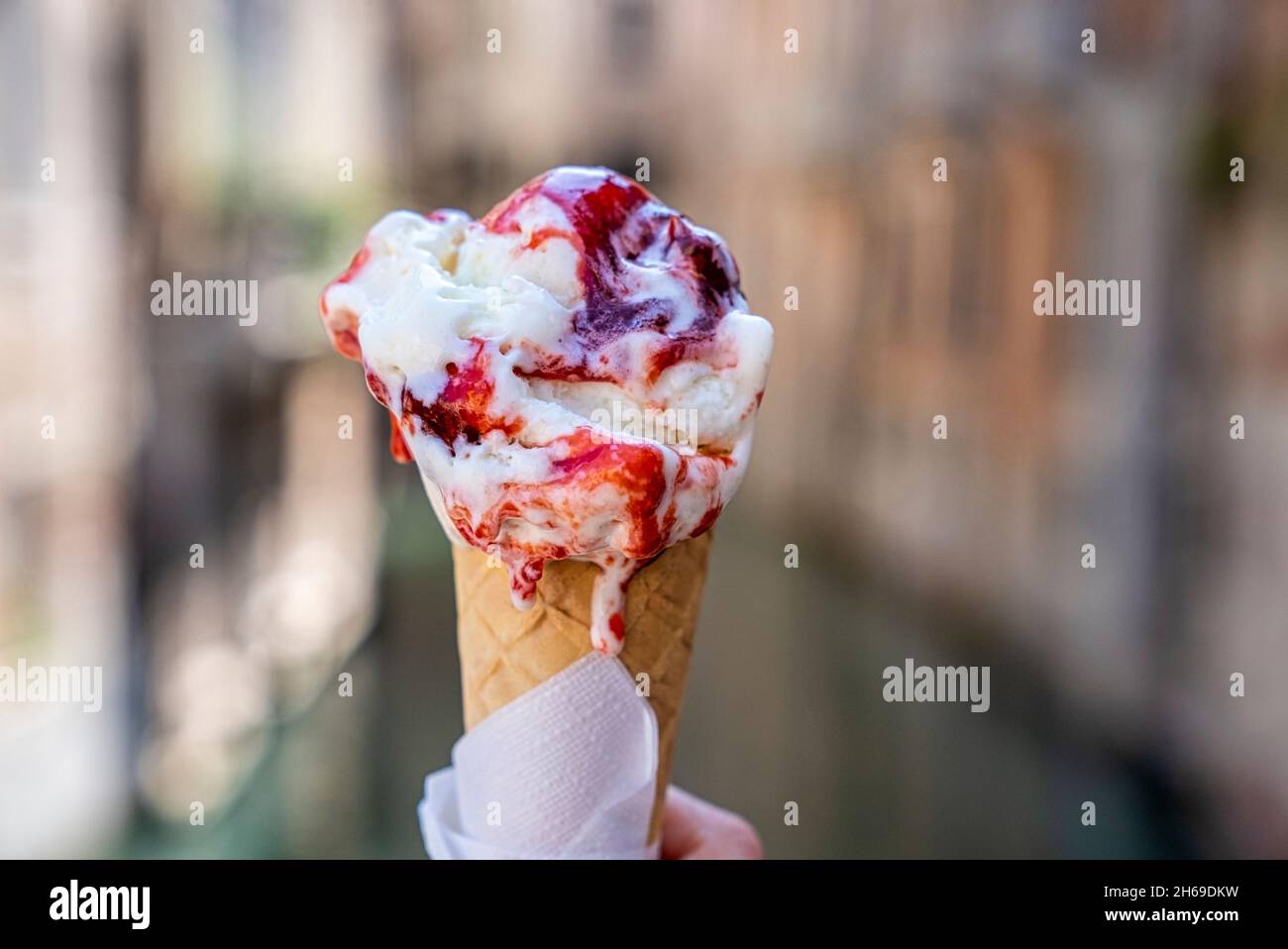 Tenere a mano delizioso fondente gelato alla fragola cono gelato Foto Stock