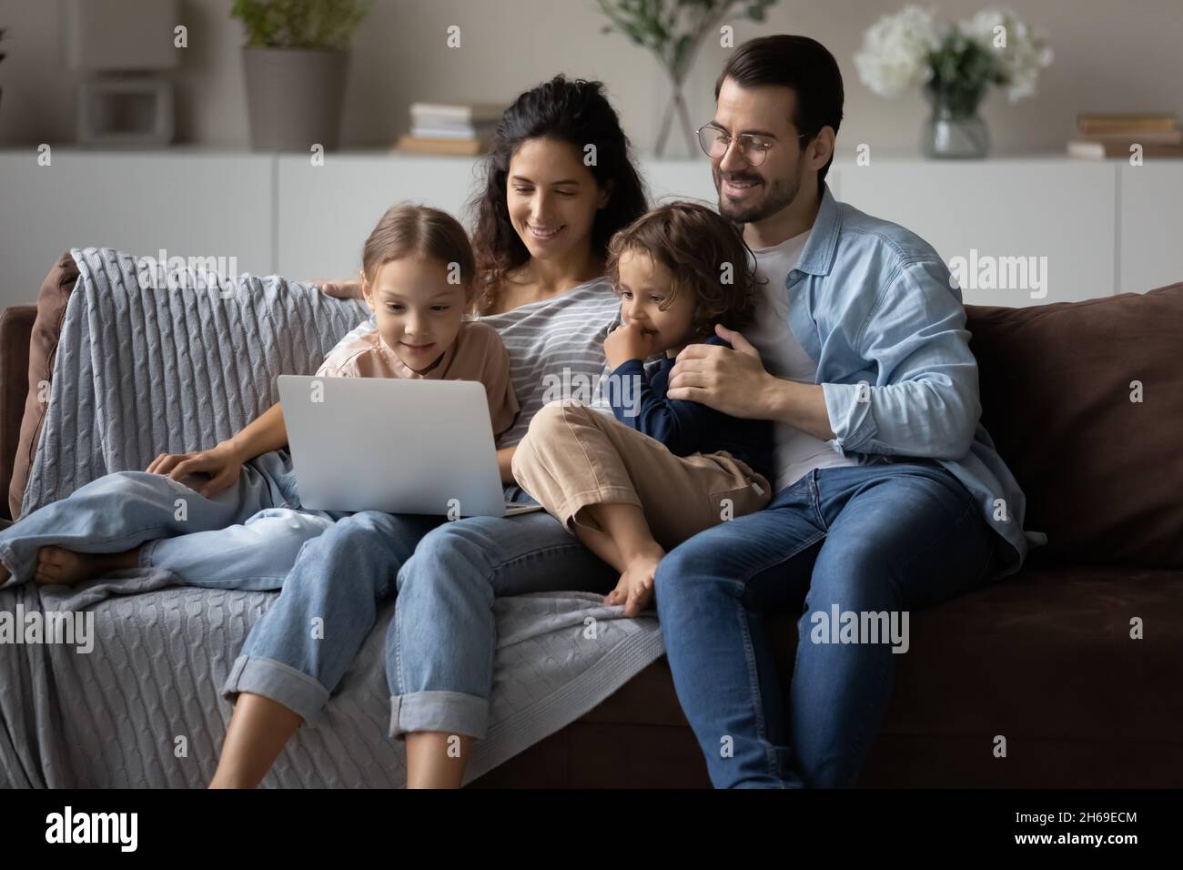 Felici i genitori con i bambini che usano il notebook a casa insieme Foto Stock