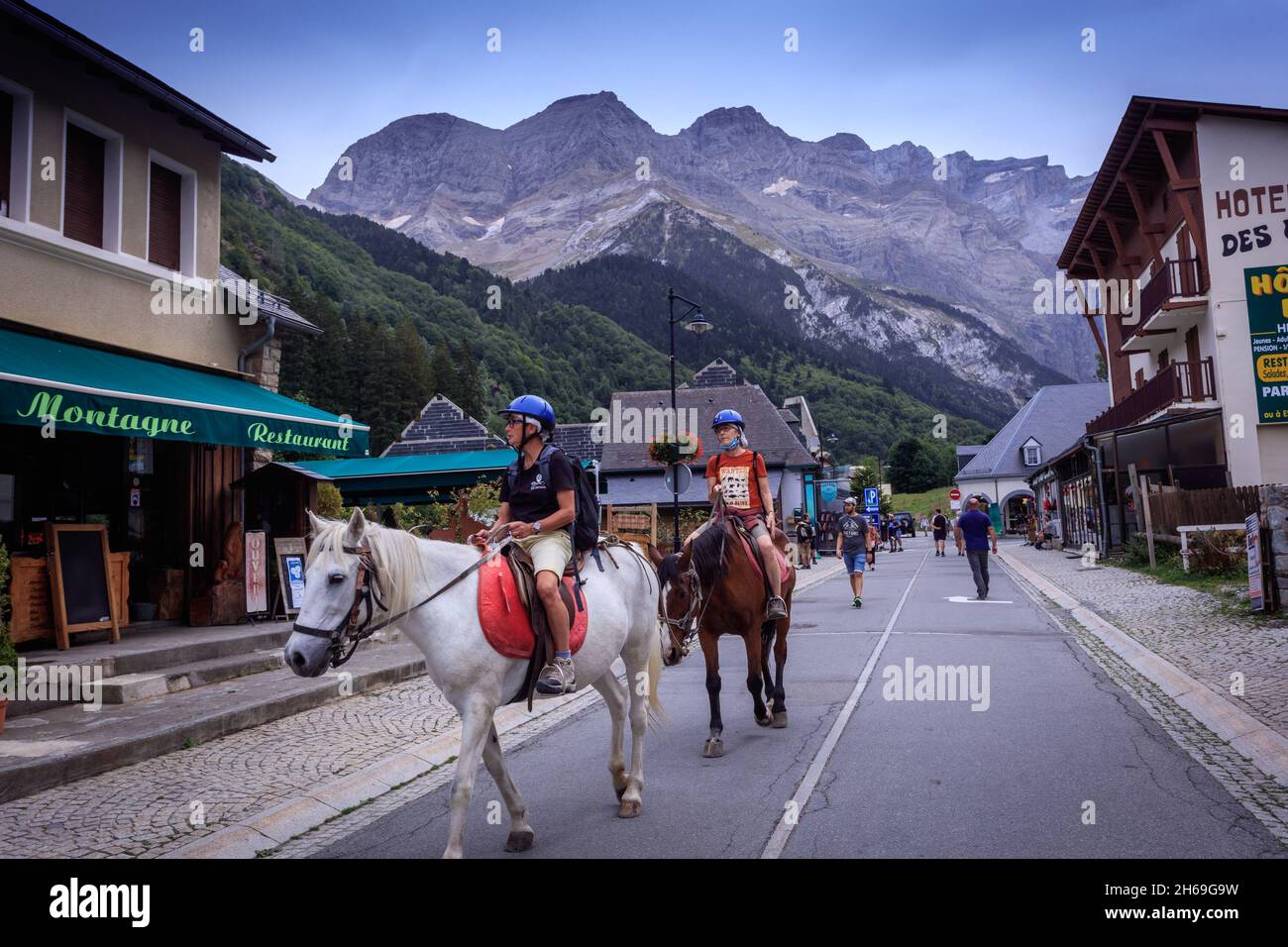 I turisti cavalcano i cavalli a Gavarnie, nel Parco Nazionale dei Pirenei francesi, patrimonio dell'umanità dell'UNESCO. Foto Stock
