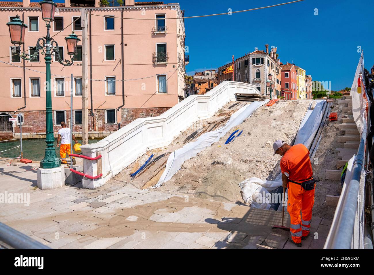Operatore che attraversa il ponte di costruzione sottostante sul canale Foto Stock