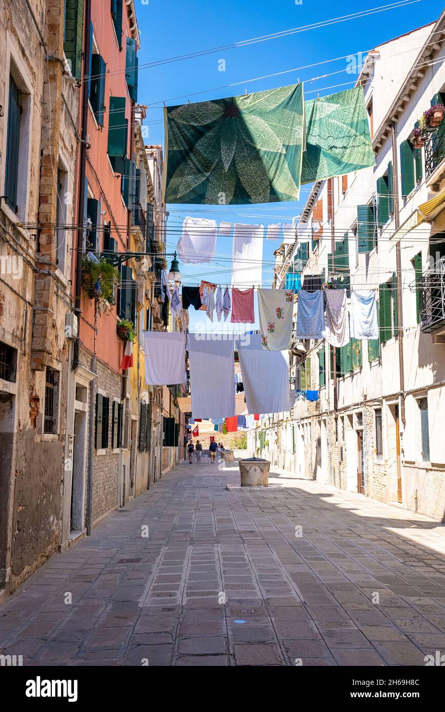 Vestiti bagnati che asciugano su clothesline sopra il vicolo tra edifici residenziali. Foto Stock