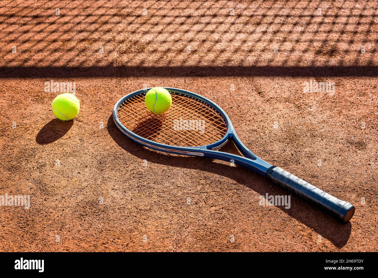 Racket da tennis e nuovo pallone da tennis su un campo di argilla rossa. Foto Stock