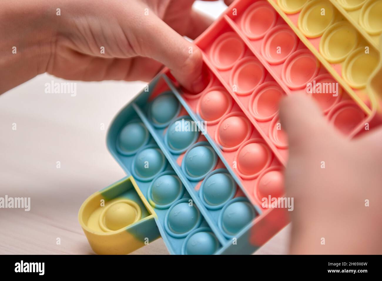 Le mani dei capretti spingono il schiocco sensoriale esso. Giocattoli antistress colorati, dimple semplice, tubo pop. Rainbow silicone sensoriale Fidget nuovo popolare giocattolo in silicone alla moda. Foto Stock