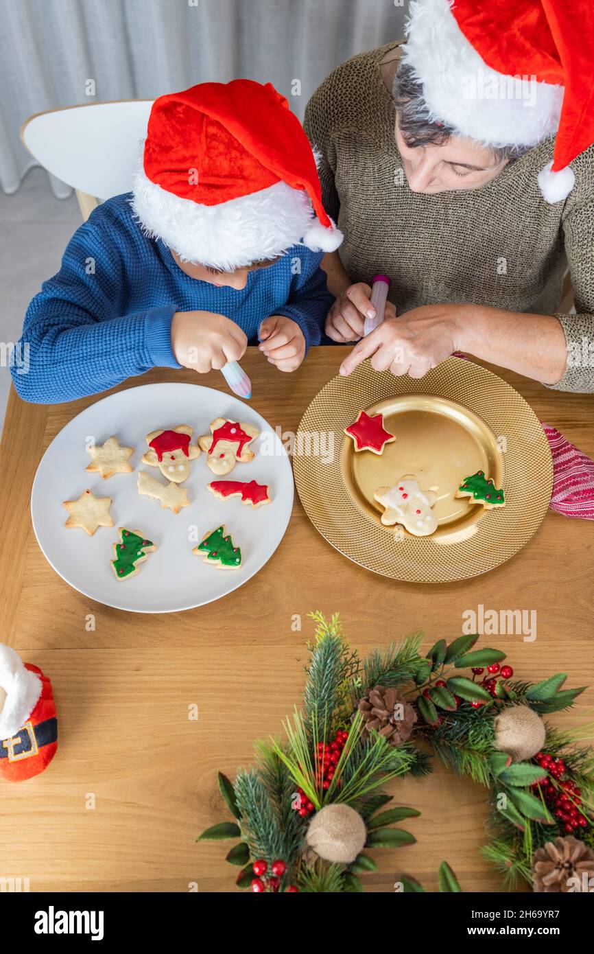 Il capretto piccolo e la sua nonna che decorano i biscotti di natale nel paese Foto Stock