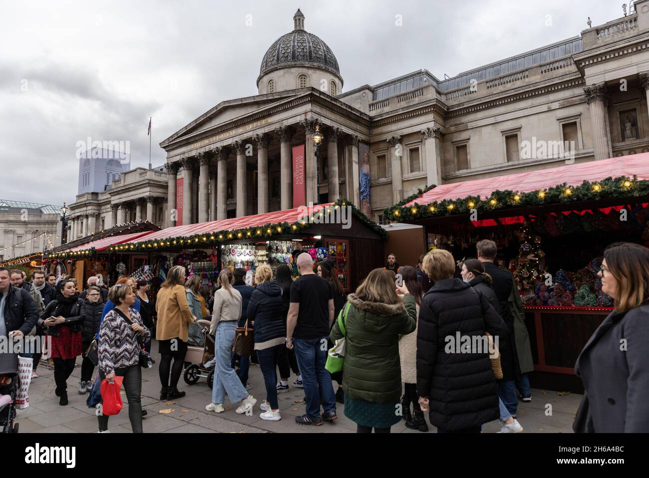 I turisti si riuniscono nel mercatino di Natale a Trafalgar Square, all'inizio della stagione festiva natalizia 2021 nella capitale, Londra, Inghilterra, Regno Unito Foto Stock