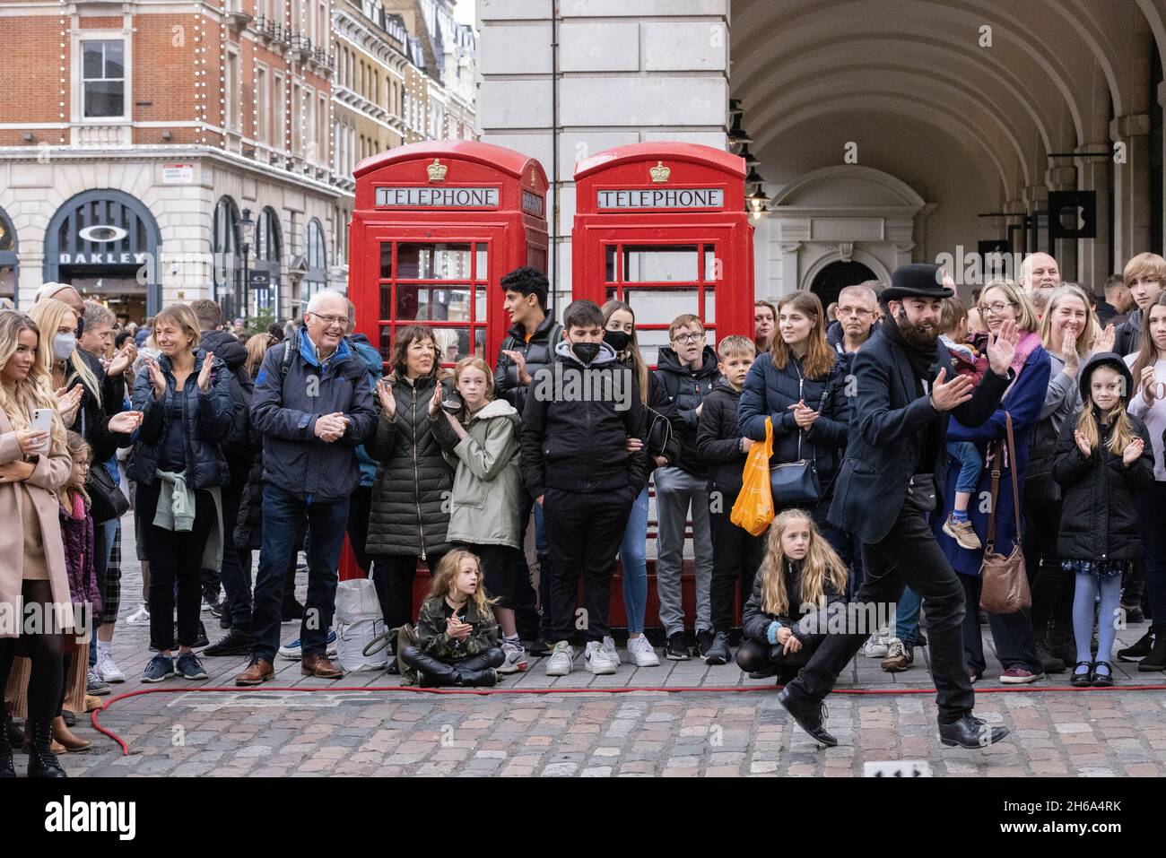Gli amanti dello shopping si riuniscono per assistere all'intrattenimento Street a Covent Garden Piazza, nel centro di Londra, Inghilterra, Regno Unito Foto Stock