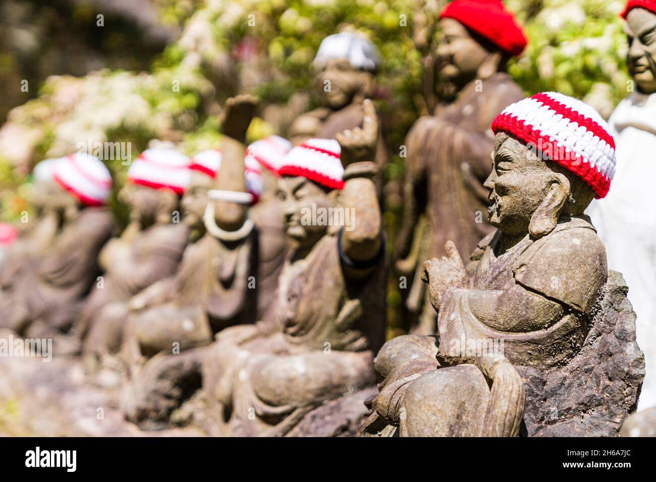 Giappone, Miyajima. Rakan piccole statue di monaci buddisti, discepoli di Shaka, rivestimento gradino di pietra percorso attraverso l'entrata del Daisho-nel tempio. Foto Stock