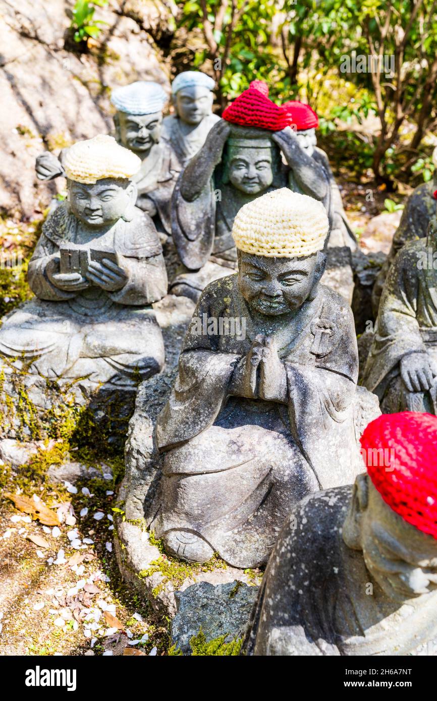 Giappone, Miyajima. Rakan piccole statue di monaci buddisti, discepoli di Shaka, rivestimento gradino di pietra percorso attraverso l'entrata del Daisho-nel tempio. Foto Stock