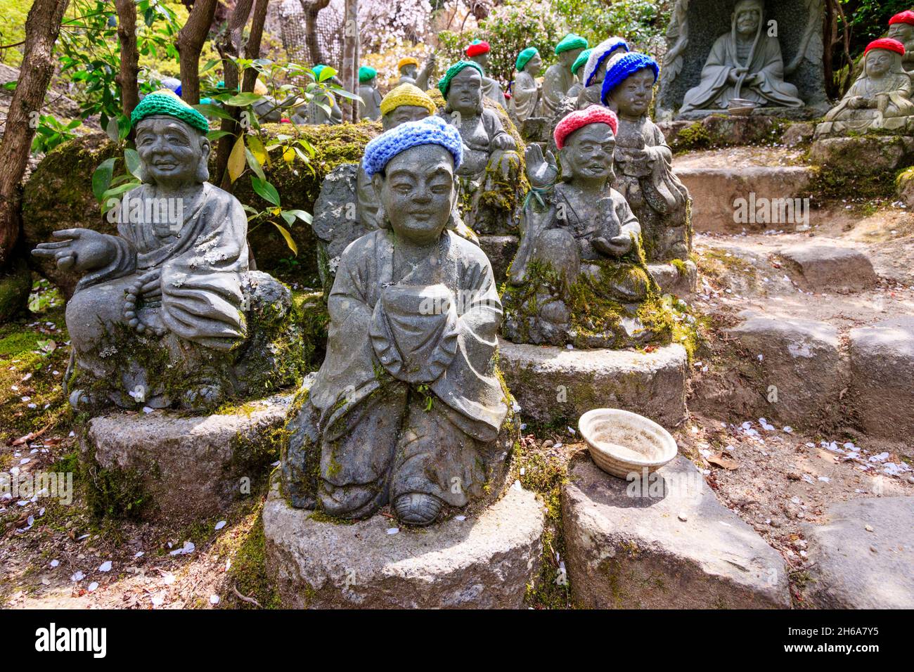 Giappone, Miyajima. Rakan piccole statue di monaci buddisti, discepoli di Shaka, rivestimento gradino di pietra percorso attraverso l'entrata del Daisho-nel tempio. Foto Stock