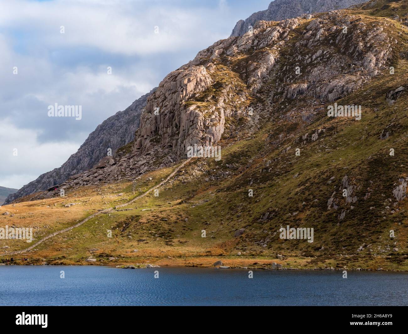 Una bella montagna bagnata dalla luce del sole autunnale sopra un lago a Snowdonia, Galles Foto Stock
