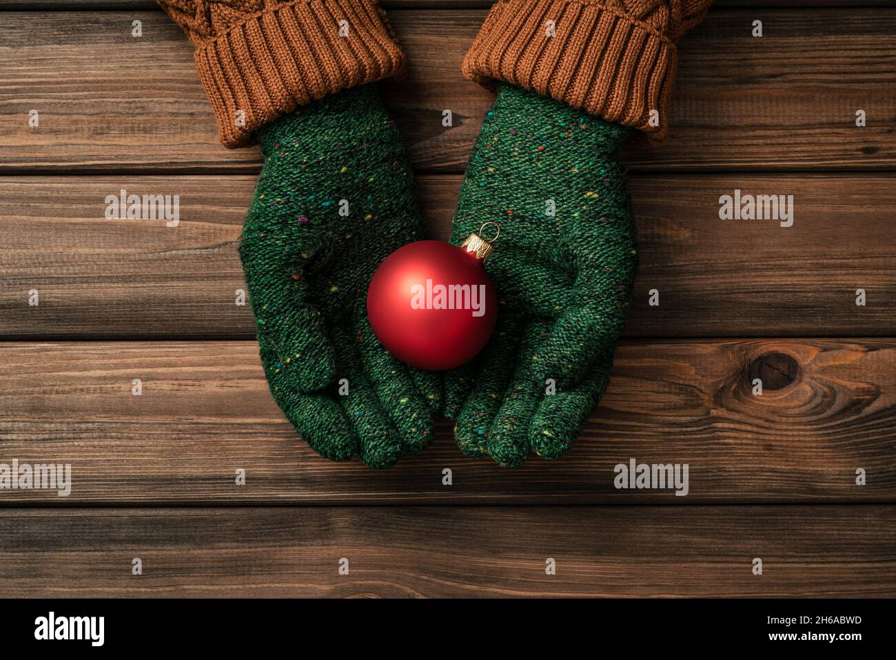 Biglietto di Natale con palla di natale in mani donna su sfondo di legno Foto Stock