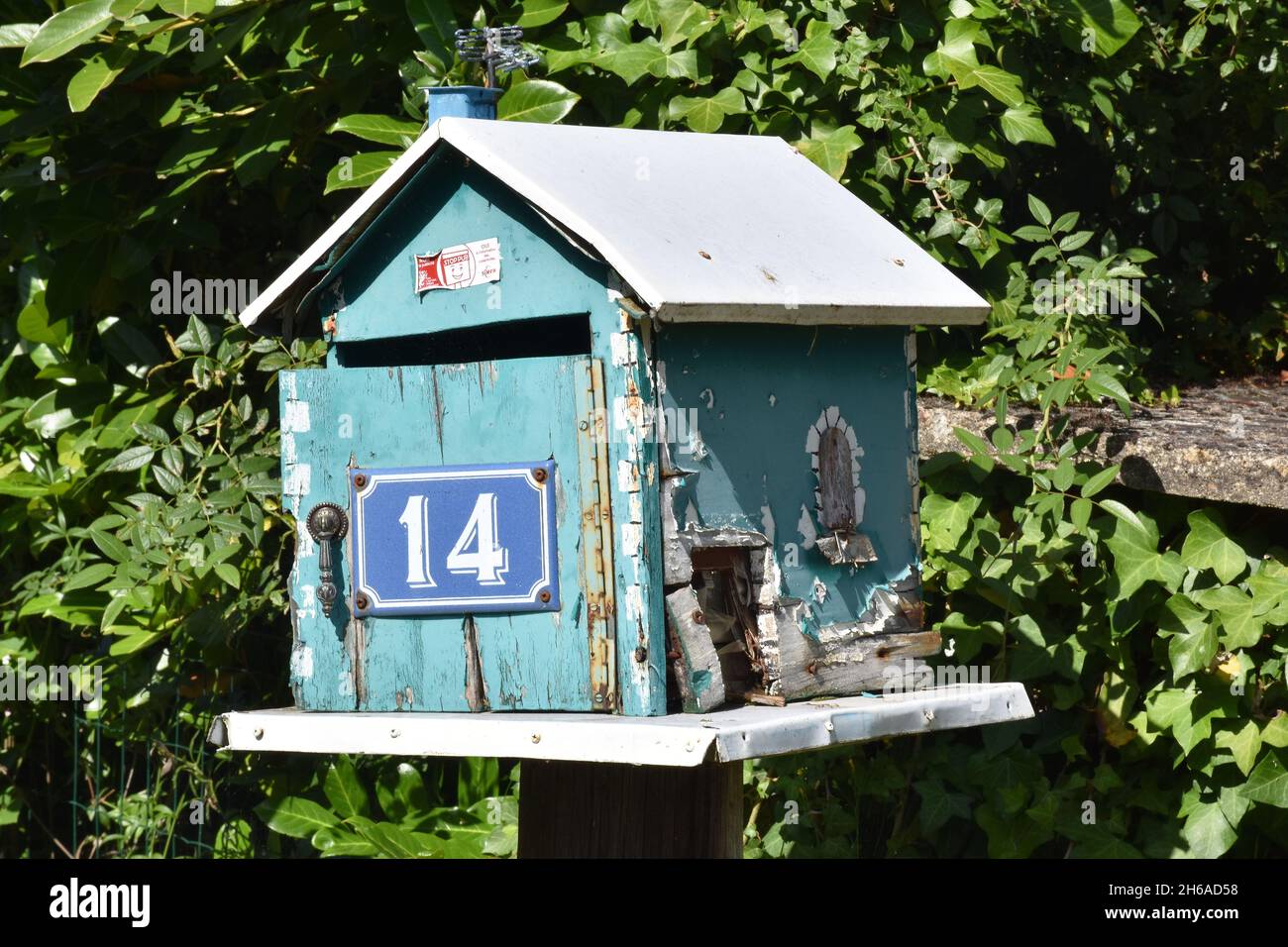 Una mailbox fatta in casa, una scatola in legno color turchese a forma di casa con tetto a falde e l'intera apertura frontale su cerniera a piano Foto Stock