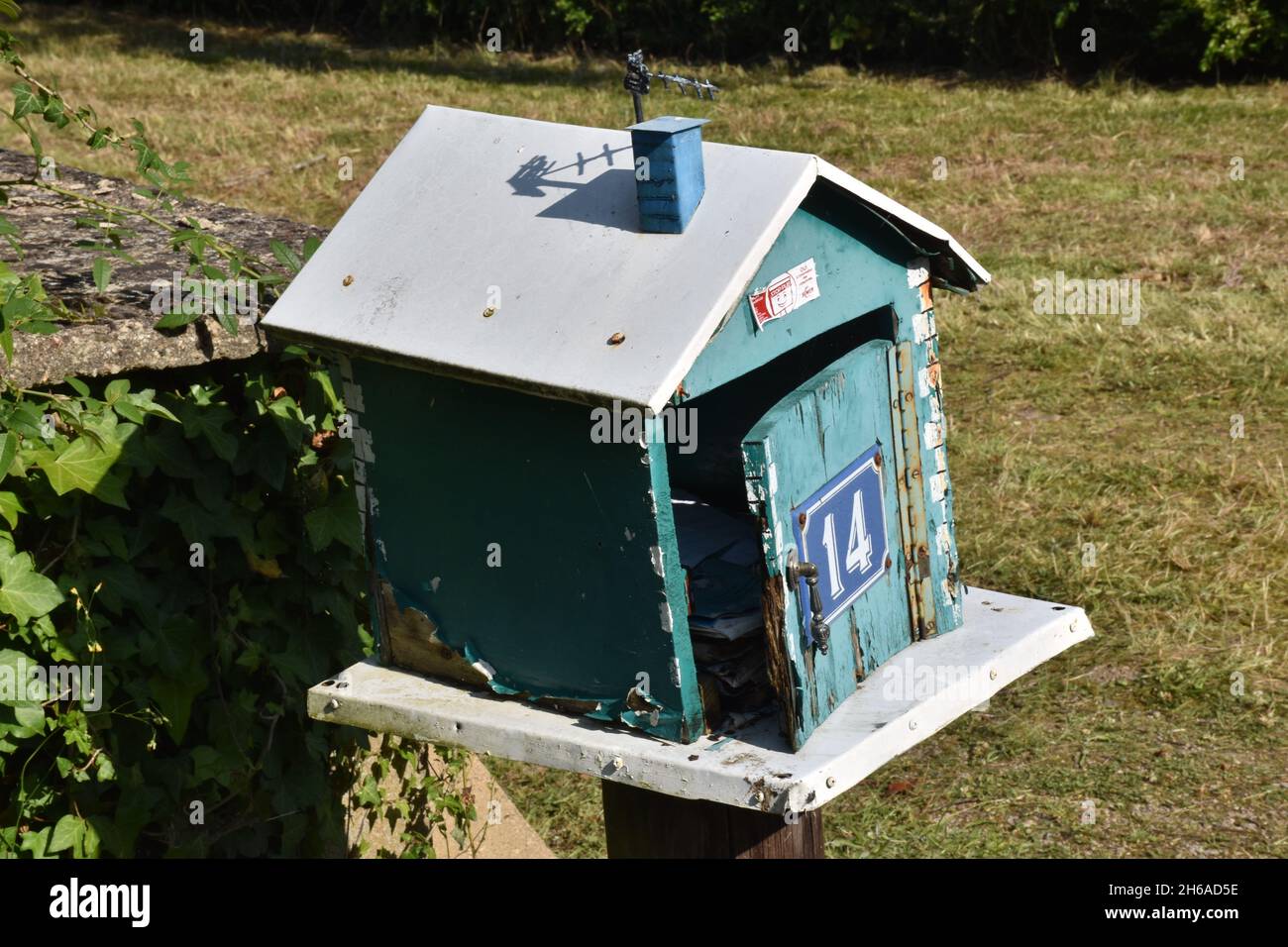 Una mailbox fatta in casa, una scatola in legno color turchese a forma di casa con tetto a falde e l'intera apertura frontale su cerniera a piano Foto Stock