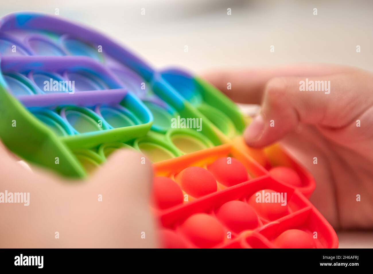 Le mani dei capretti spingono il schiocco sensoriale esso. Giocattoli antistress colorati, dimple semplice, tubo pop. Rainbow silicone sensoriale Fidget nuovo popolare giocattolo in silicone alla moda. Foto Stock