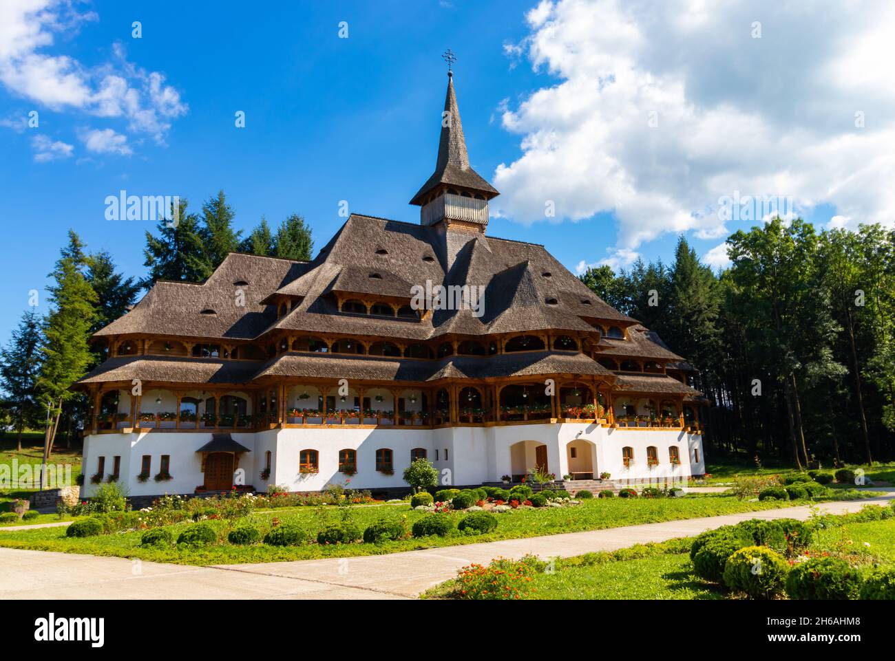 Edificio con torri e tetto in legno, in particolare Maramures dal cortile del monastero di Peri-Sapanta, che ha un'alta croce sul tetto Foto Stock