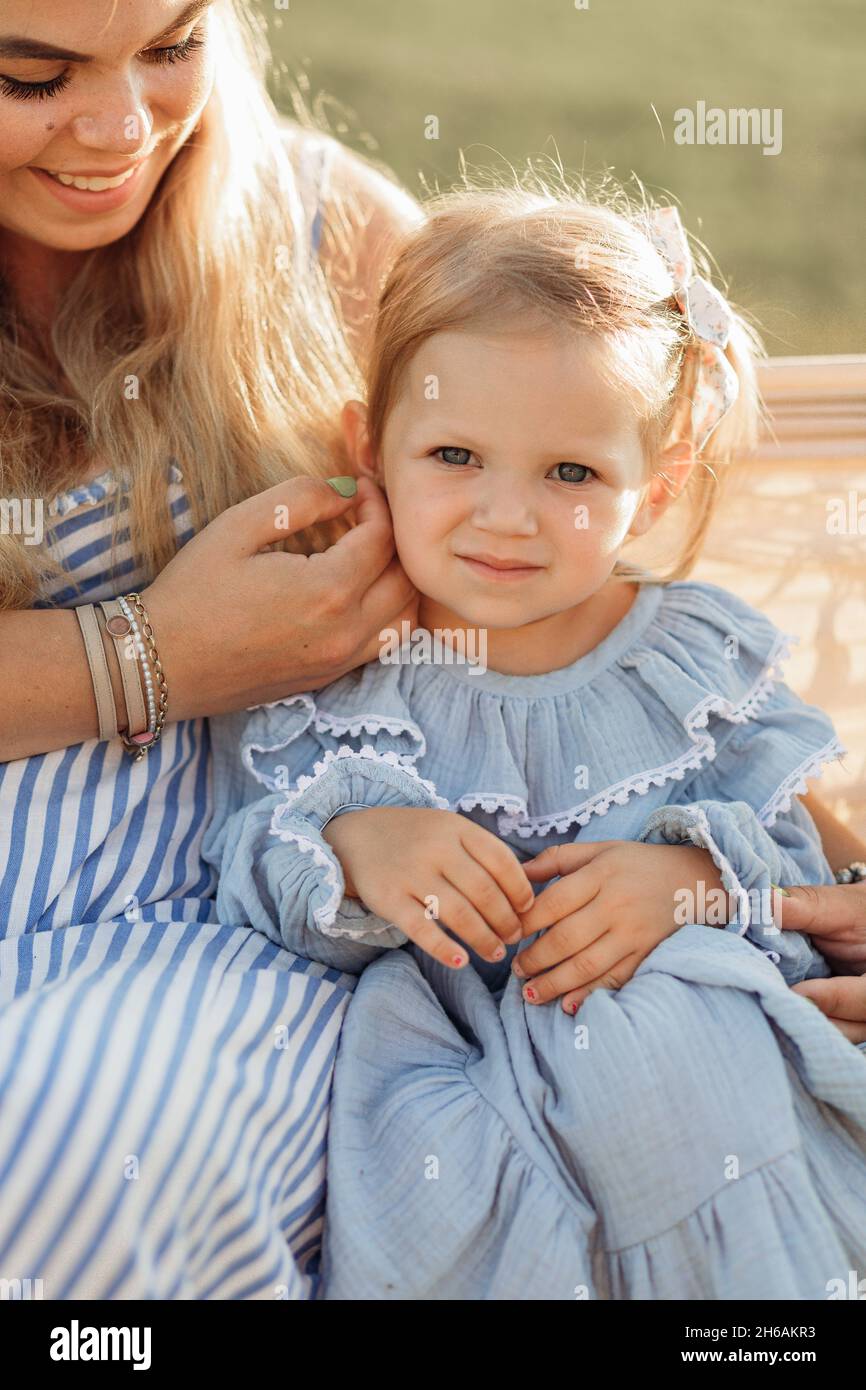 Ritratto estivo in natura di mamma e figlia bionda, vestito con abiti blu in materiali naturali. Bambini di 3 anni. Buona infanzia, madre Foto Stock