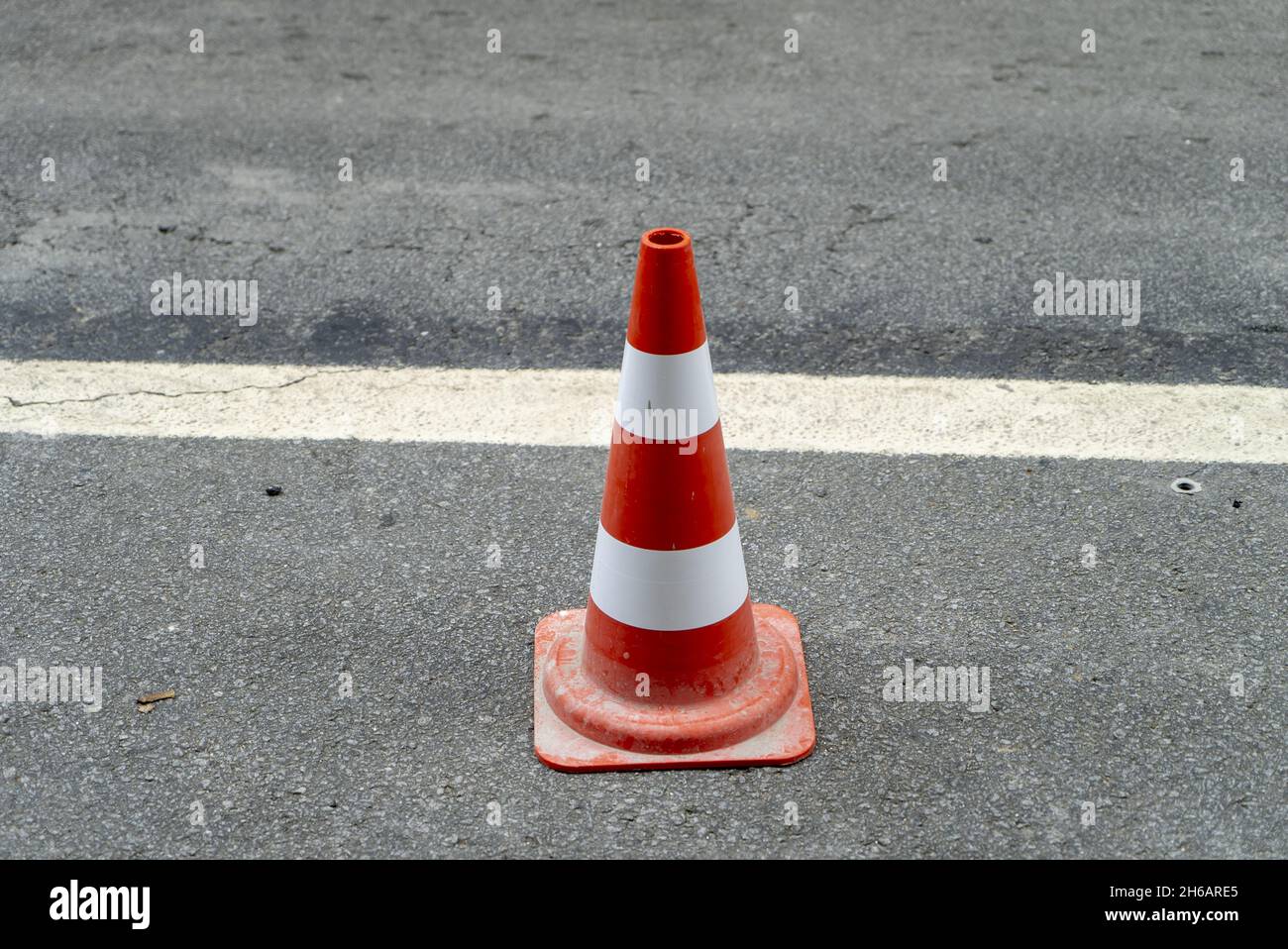 Un cono di traffico rosso sulla strada per una deviazione temporanea del traffico in modo sicuro Foto Stock