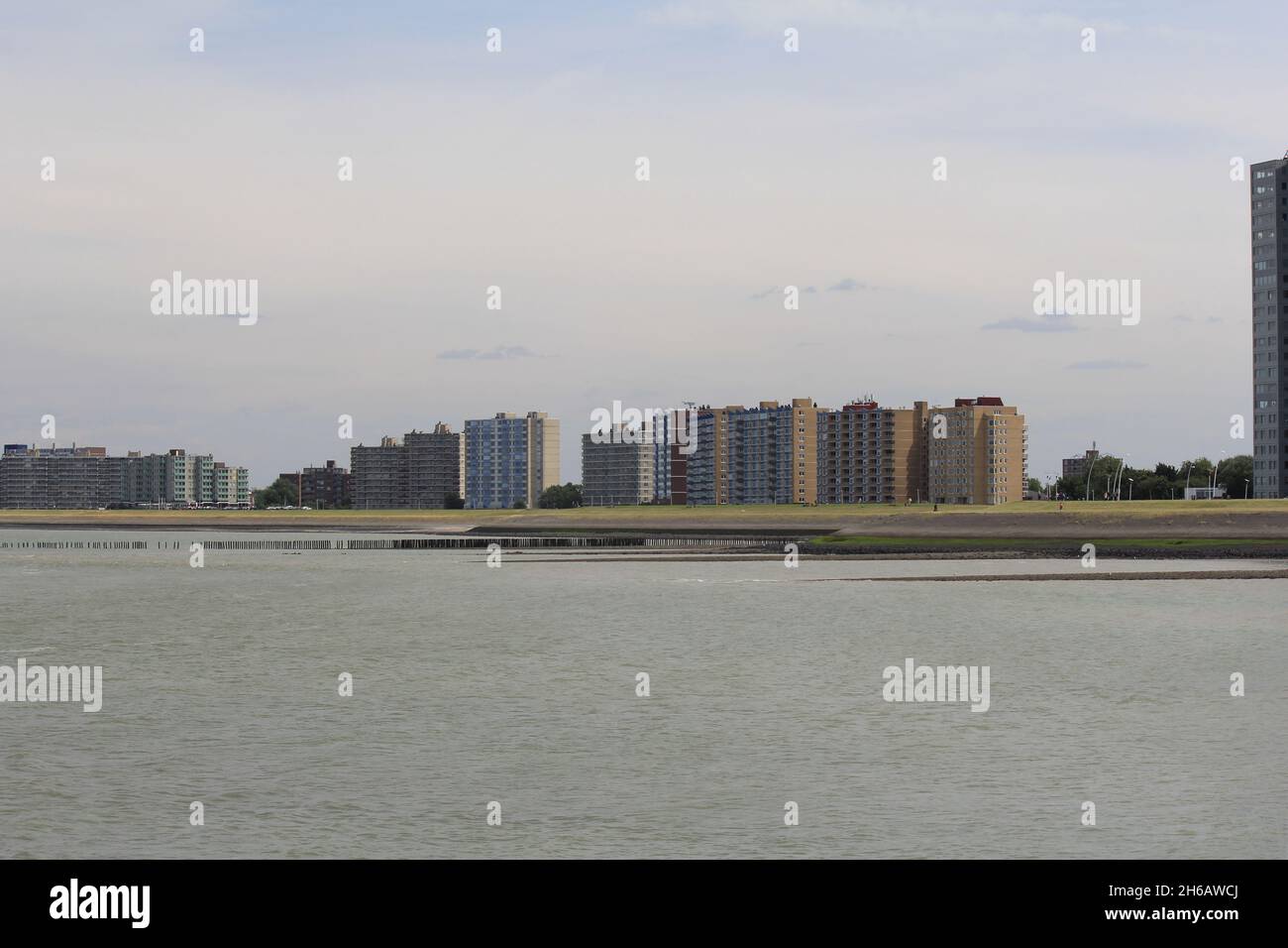 una fila di appartamenti dietro la parete del mare westerschelde sulla costa olandese a terneuzen in estate con l'alta marea Foto Stock