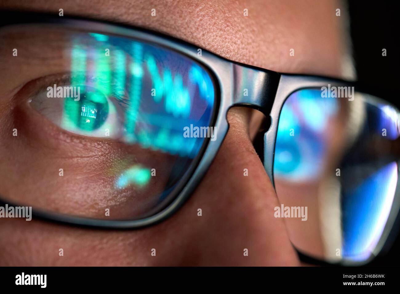 Trader guardando lo schermo del calcolatore che analizza la tabella di commercio che riflette negli occhiali. Foto Stock