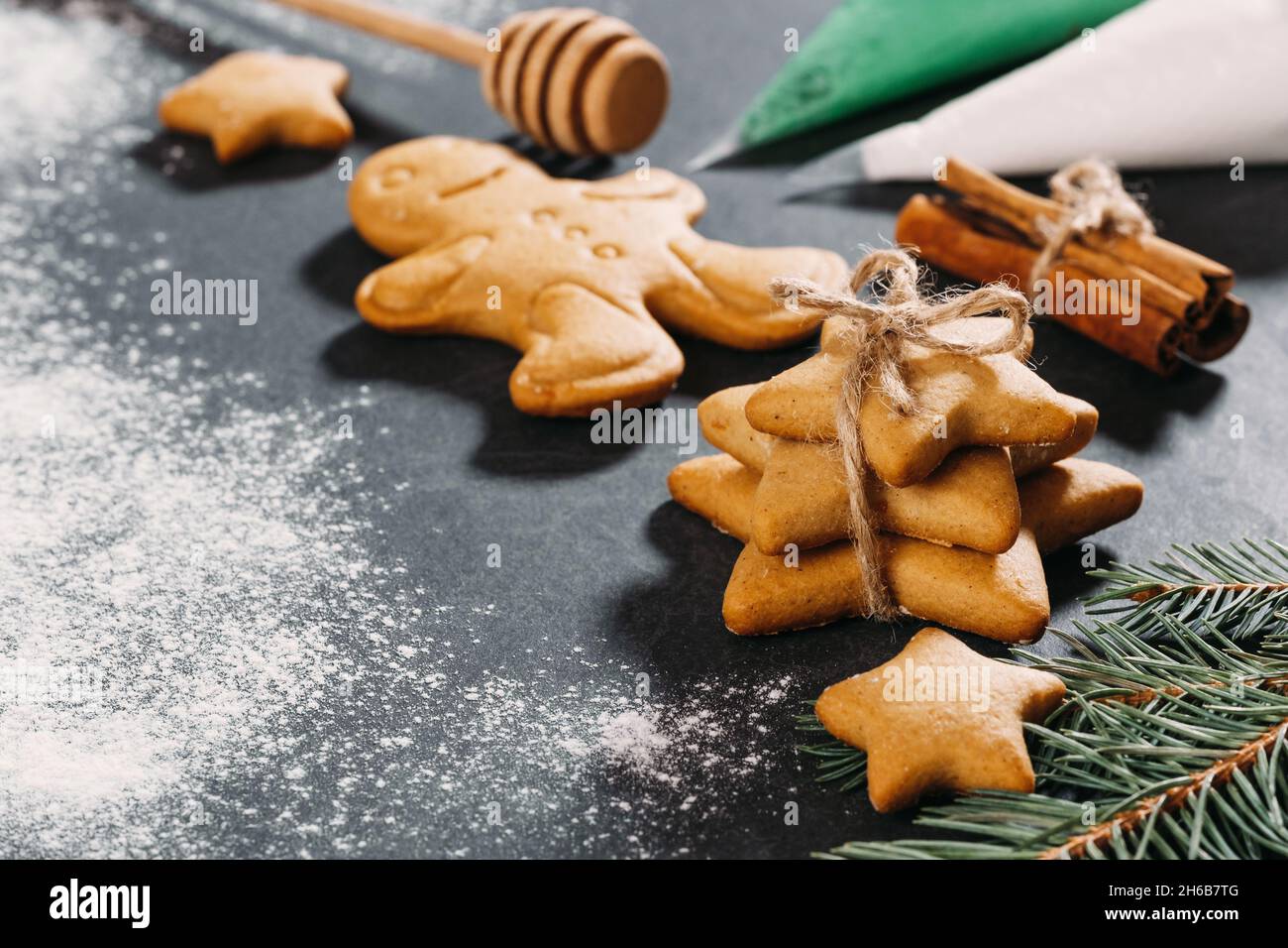 Sfondo natalizio con biscotti di zenzero fatti in casa a forma di stella con glassa sul tavolo nero, spazio copia. Cibo festivo, cartolina, festa Foto Stock