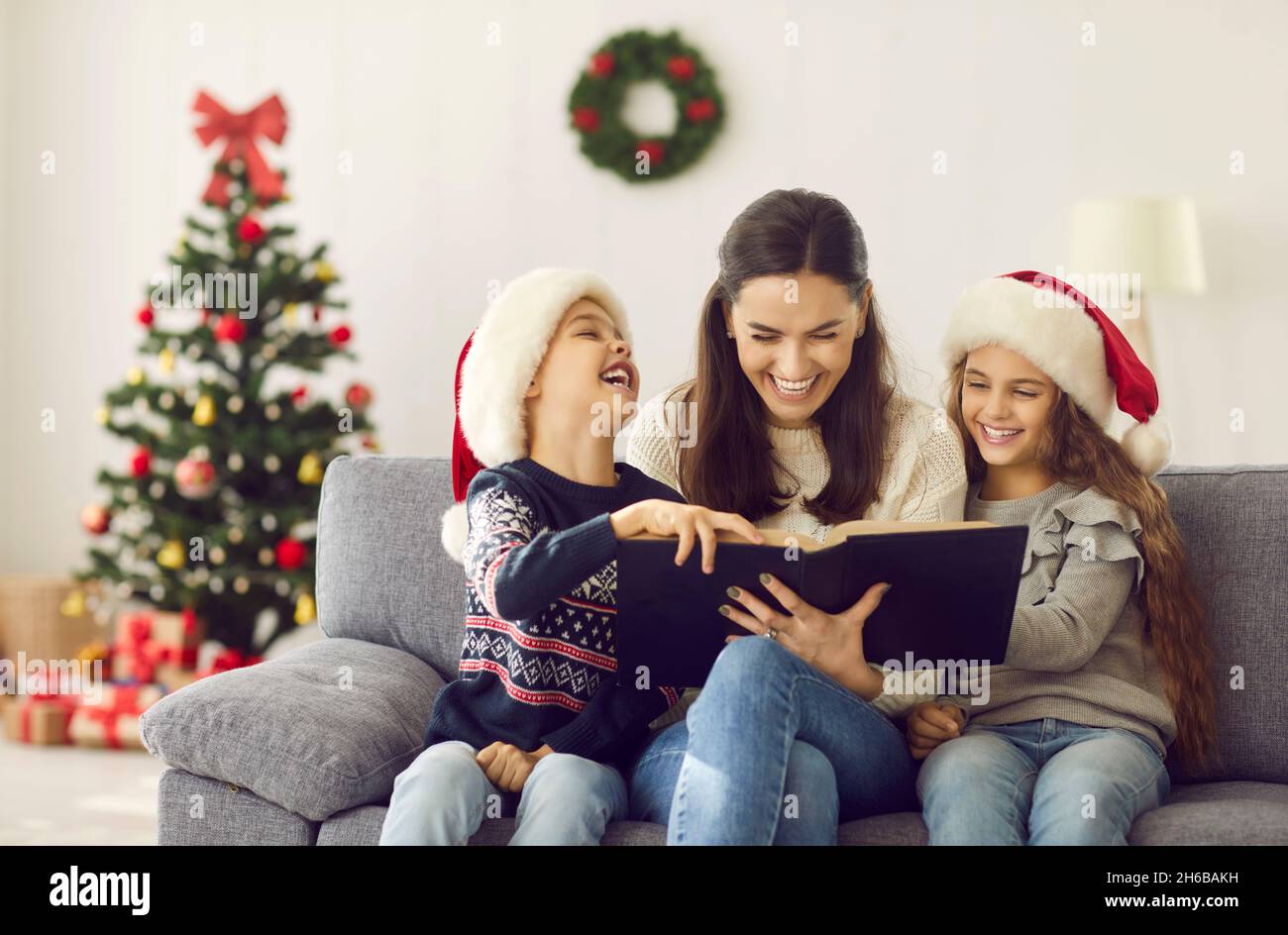 Buona madre e bambini leggere libri divertenti e divertirsi durante le vacanze di Natale Foto Stock