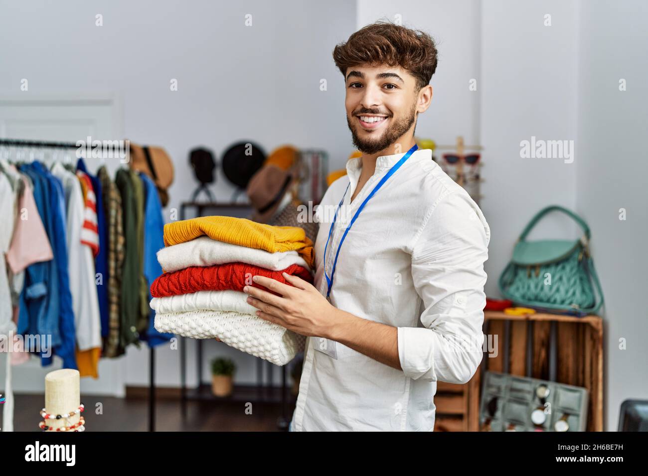 Giovane negoziante arabo che tiene vestiti piegati che lavorano al negozio  di abbigliamento Foto stock - Alamy