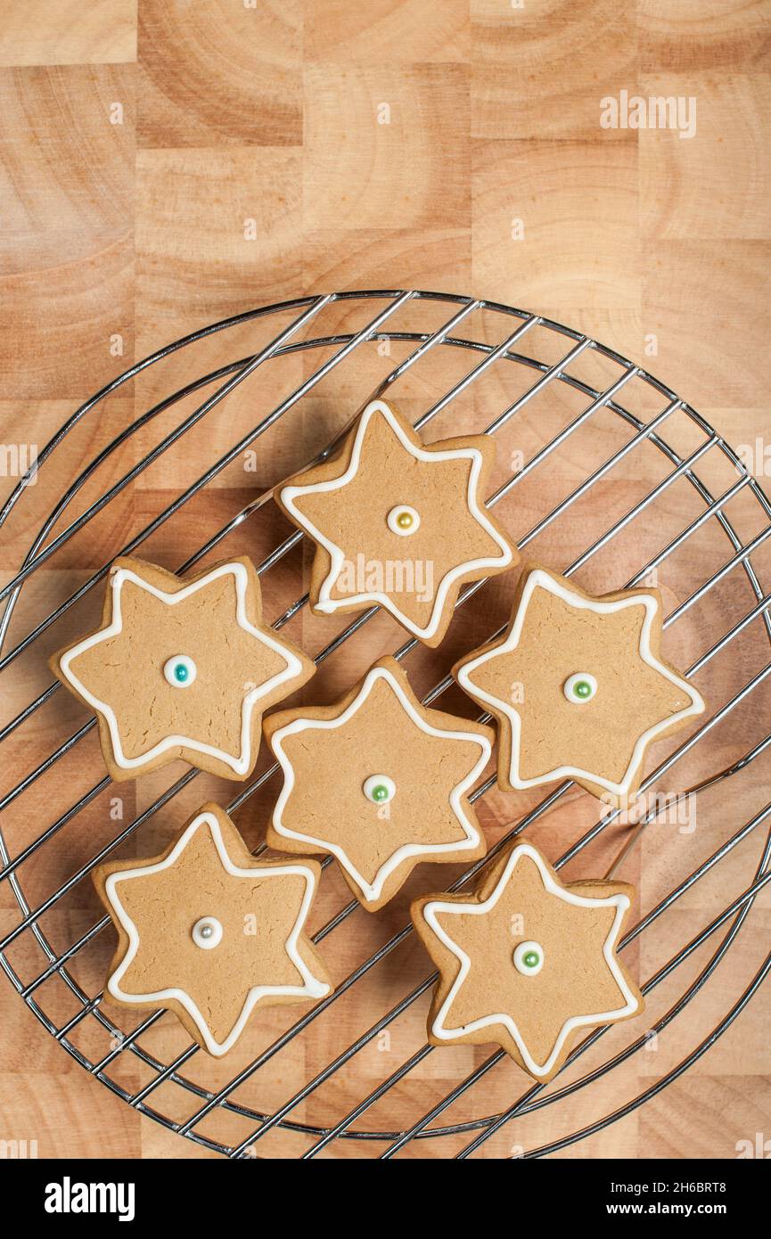 Biscotti Star pan di zenzero con glassatura su griglia di raffreddamento, asse di legno Foto Stock