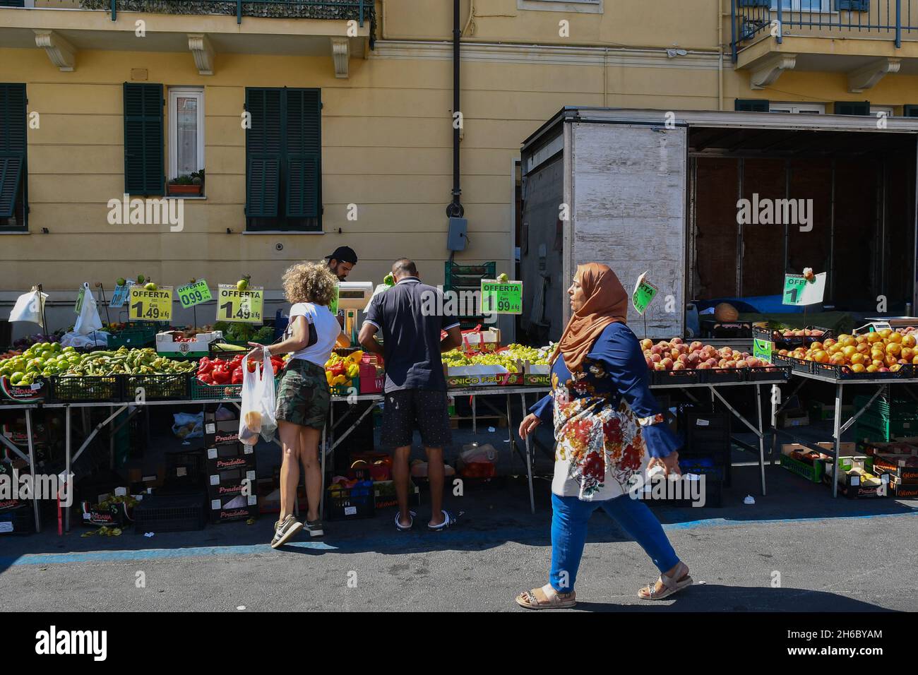 Persone che acquistano cibo fresco in una bancarella di frutta e verdura al mercato settimanale nel centro della città di Alassio in estate, Savona, Liguria, Italia Foto Stock