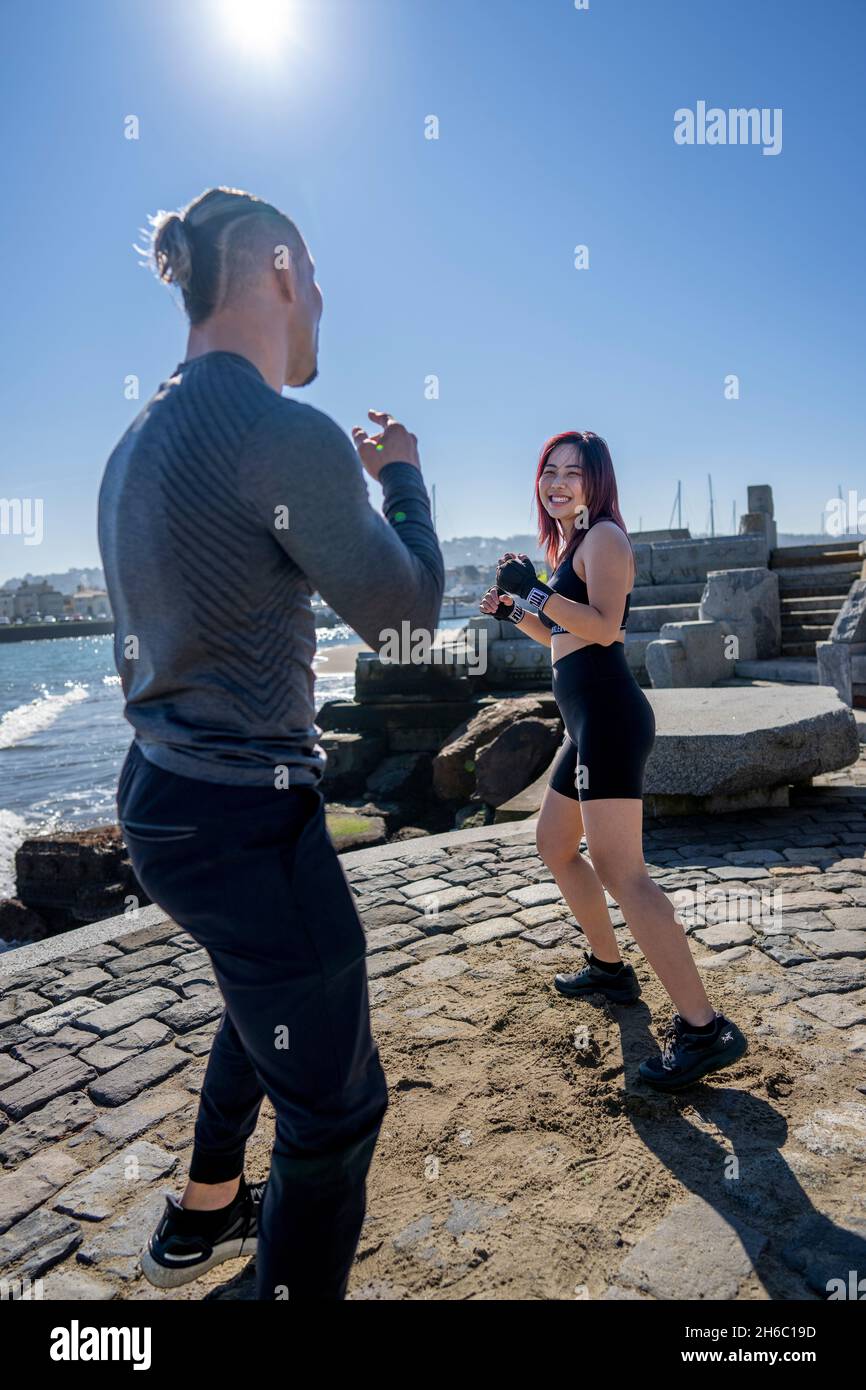 Giovane donna asiatica che prende la prima sessione di formazione MMA con personal trainer Foto Stock