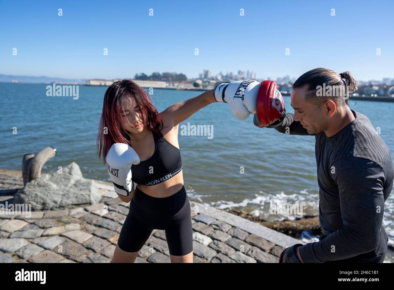 Giovane donna asiatica che prende la prima sessione di formazione MMA con personal trainer Foto Stock