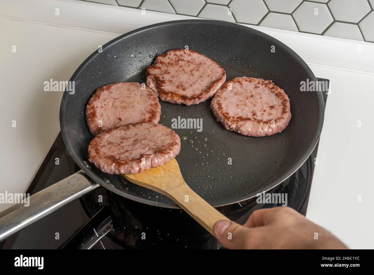 cottura degli hamburger di manzo su una padella antiaderente Foto Stock