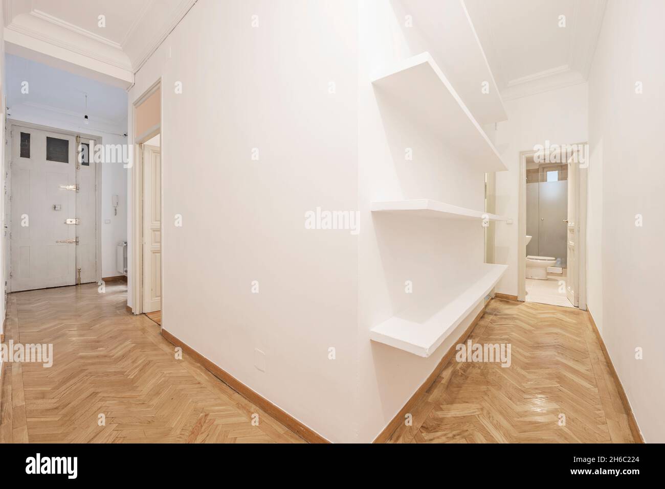 Corridoi di una casa con pavimenti in parquet, mensole in gesso e pareti dipinte di fresco Foto Stock