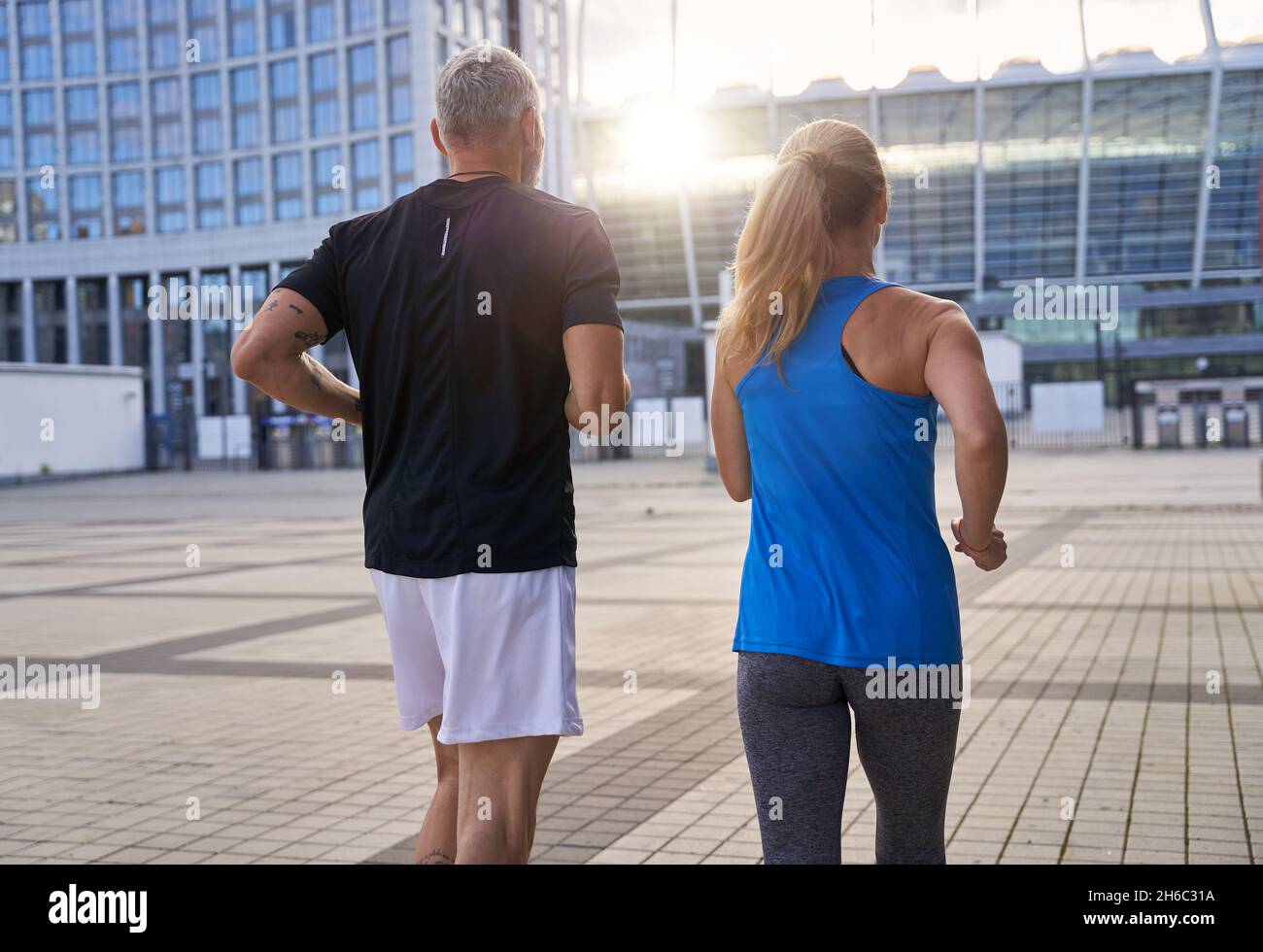 Vista posteriore di una coppia sportiva di mezza età che rimane attiva, che corre insieme in ambiente urbano Foto Stock