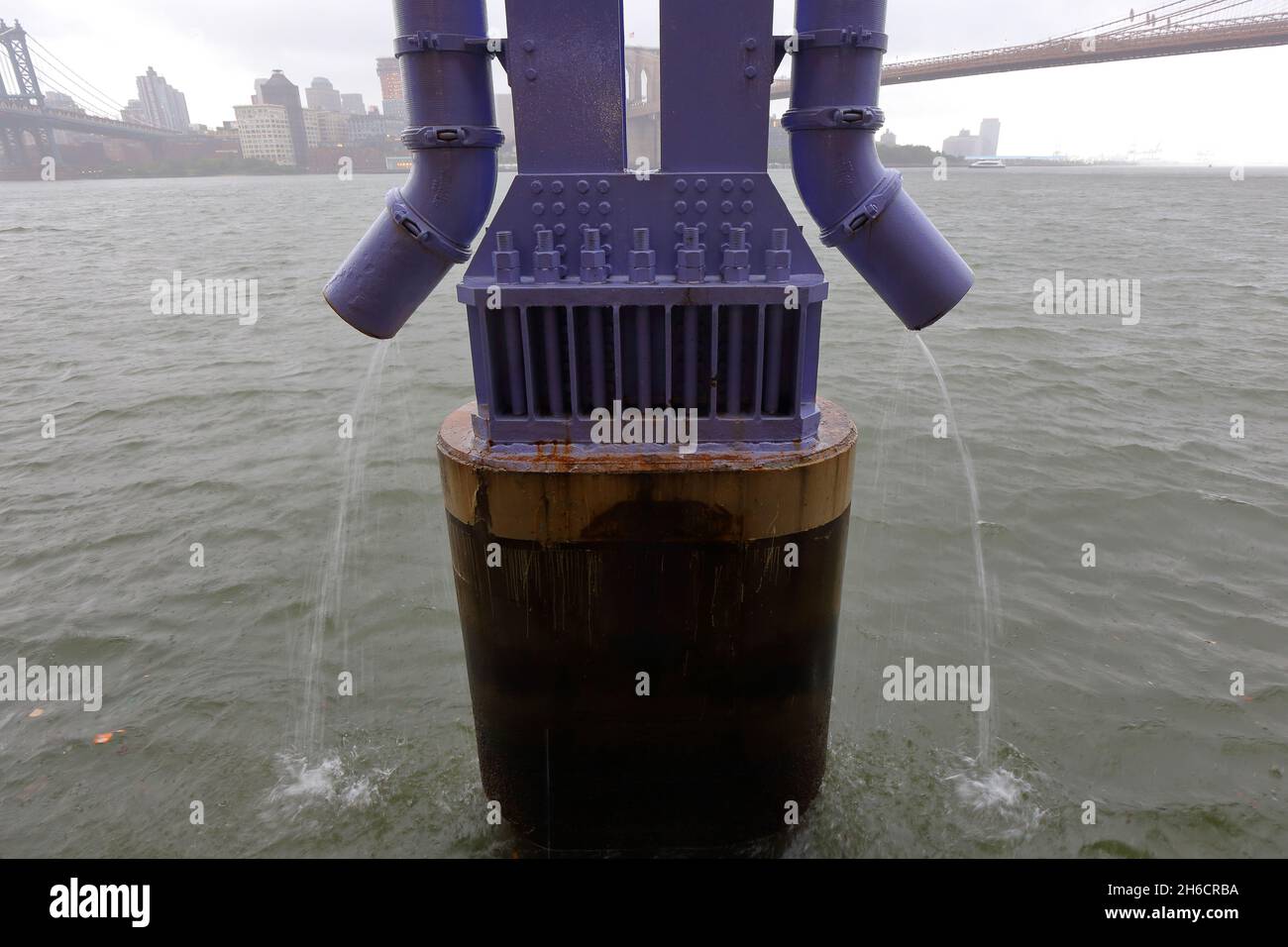 I tubi di scarico per il tempo umido fungono da imbuto per il deflusso dell'autostrada FDR e l'inquinamento, incluso il 6PPD-chinone, che si riversa nell'East River durante una tempesta di pioggia a New York City. Foto Stock