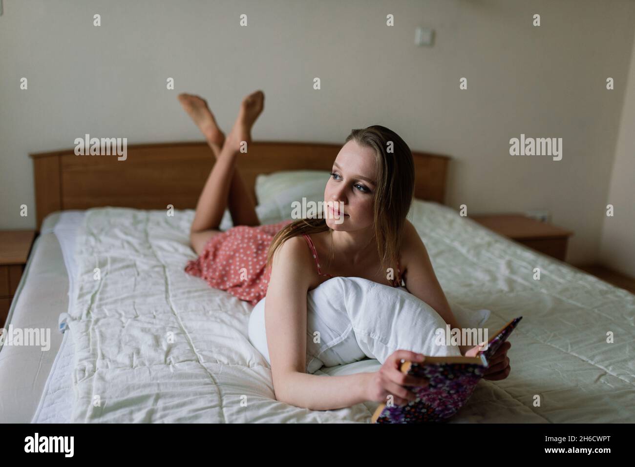 Pensive Dreamy femmina tenere libro a casa guardando grande finestra sognare, pensieroso giovane donna, studente Foto Stock