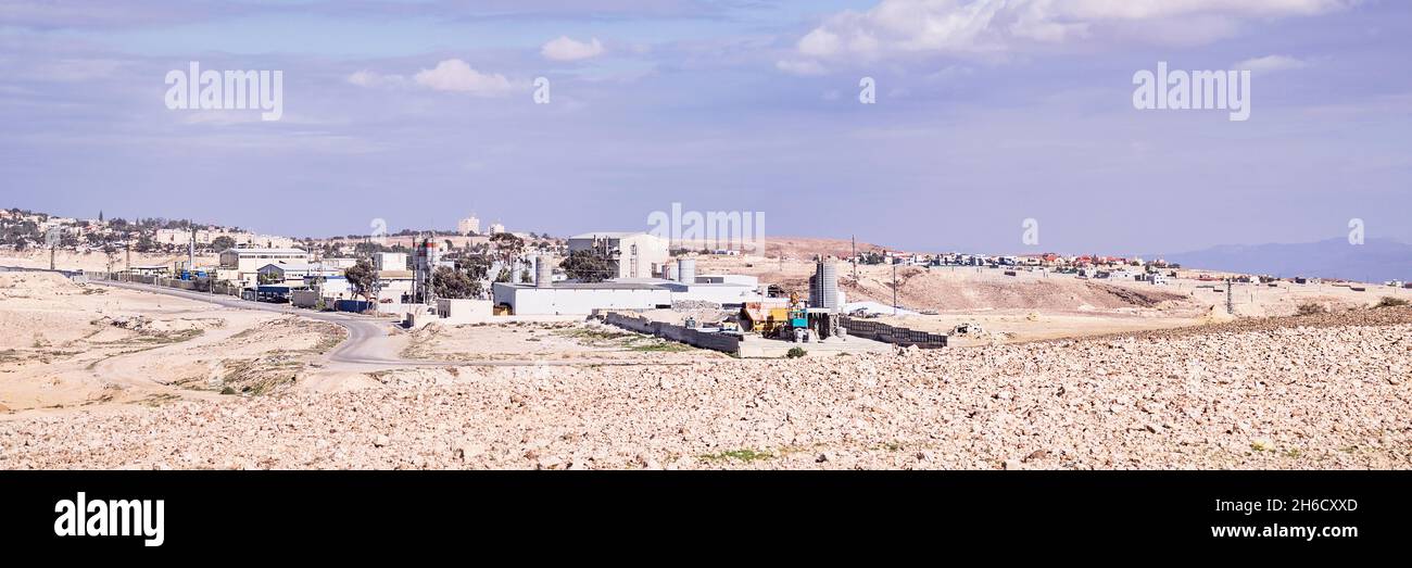 Zona industriale della città Negev di Arad in Israele con zone residenziali e nuvole sullo sfondo e deserto arido in primo piano Foto Stock