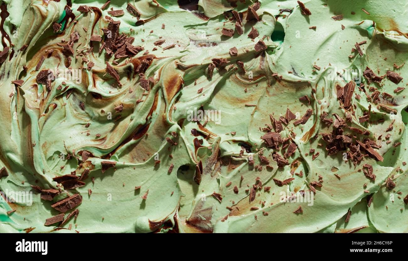Menta, tè verde giapponese o gelato matcha con fiocchi di cioccolato in una texture di fondo testurizzata e vorticosa da vicino sulla superficie del dessert Foto Stock