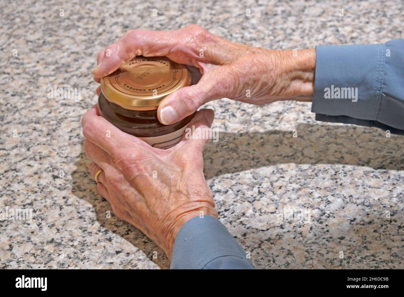 Signora anziana che apre un vaso di marmellata che mostra le sue mani invecchiamento Foto Stock