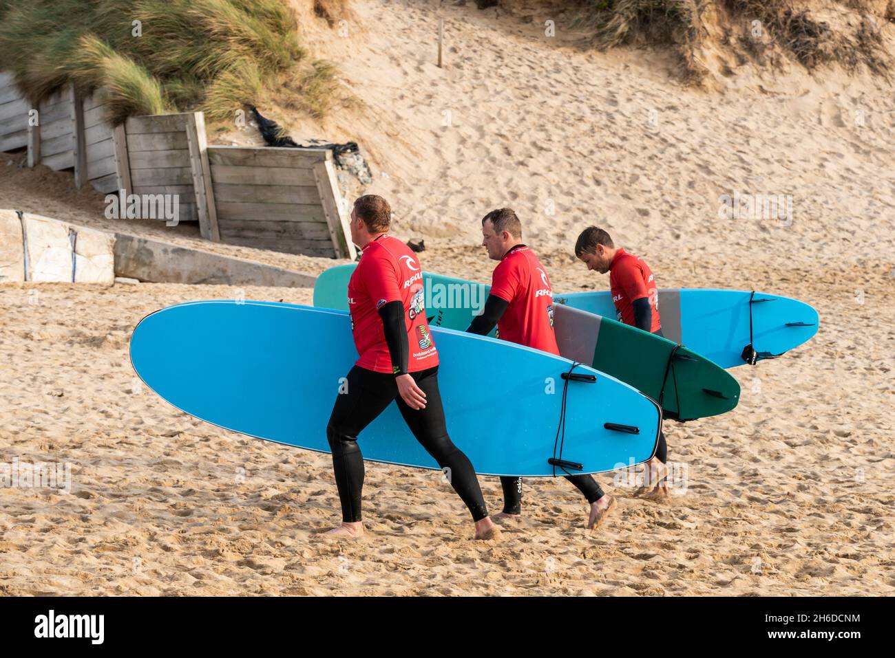 Un gruppo di surfisti maschi che restituiscono le tavole da surf noleggiate al negozio di noleggio surf Fistral a Newquay in Cornovaglia. Foto Stock