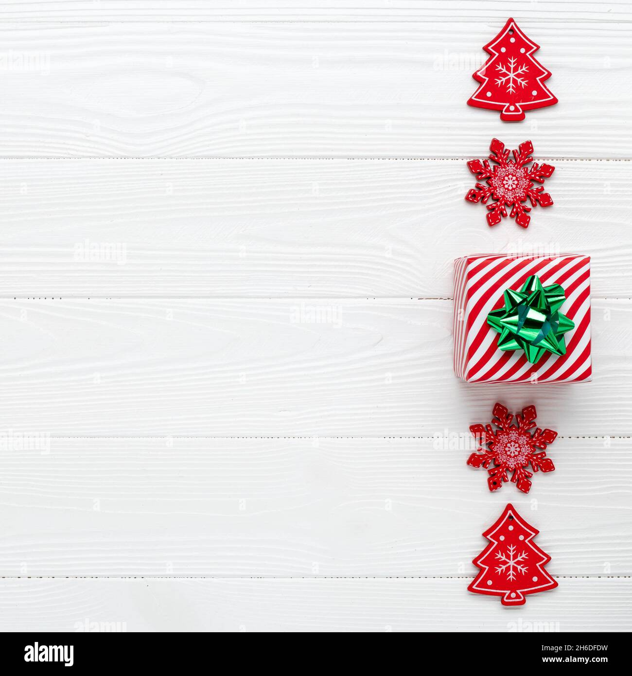 Biglietto di auguri natalizio bianco con fiocchi di neve rossi e una confezione regalo per le feste. Sfondo di nuovo anno con decorazioni. Design minimalista. Telaio con posto per t Foto Stock
