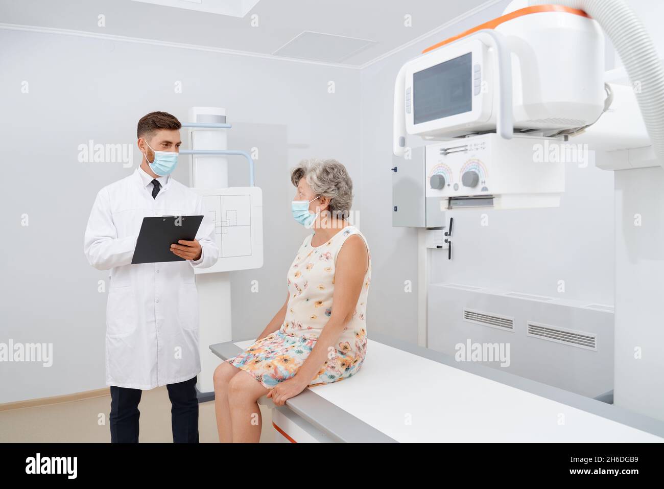 Medico che parla con la paziente di diagnostica ecografica prima dell'esame. Vecchia donna grigia con capelli in abito pronto per usg in cabinet. Concetto di medicina. Foto Stock