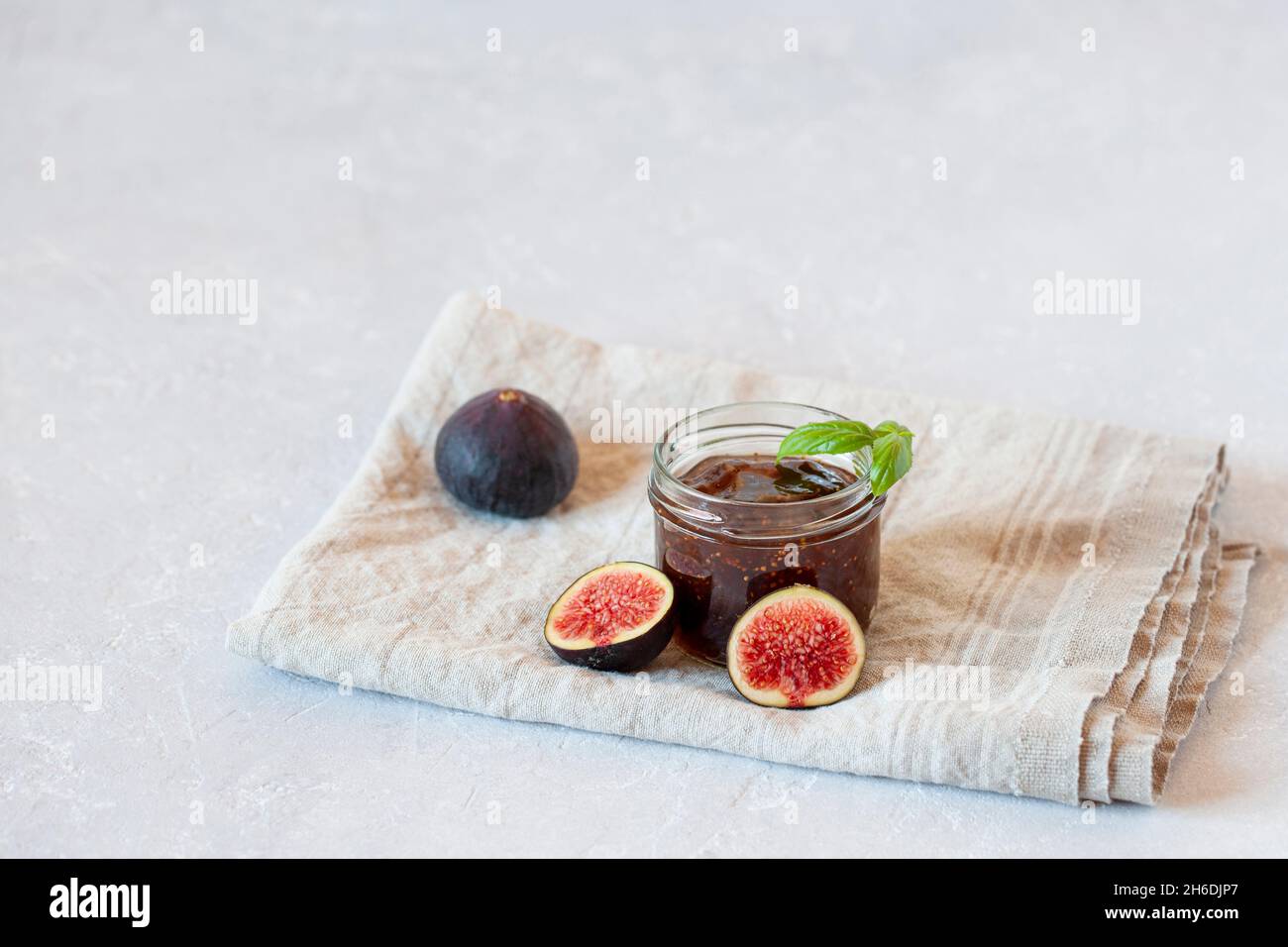 confit fico biologico fatto in casa da ricetta di famiglia in un piccolo vaso su sfondo grigio calcestruzzo, vista laterale, spazio copia Foto Stock