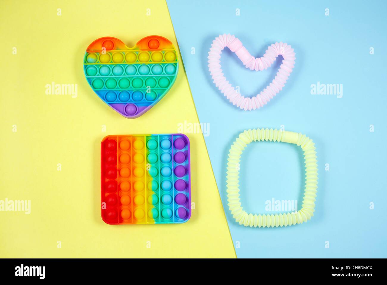 Tubi luminosi multicolore e pop su sfondo colorato. Giocattoli antistress per le dita per adulti e bambini. Foto Stock