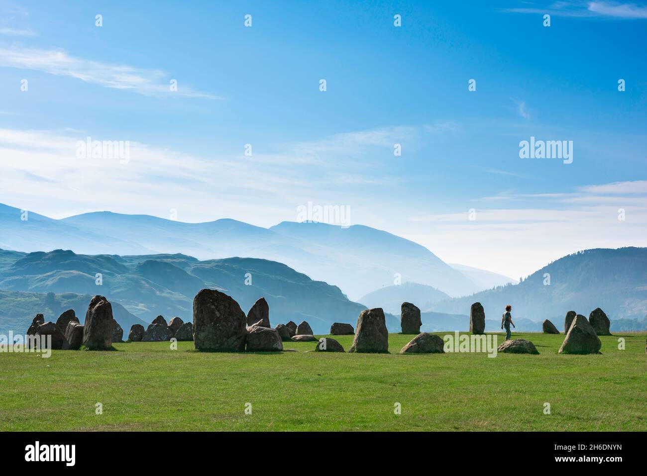 Cerchio di pietra Regno Unito, vista su una mattinata estiva di una donna che cammina all'interno di un antico cerchio di pietra sullo sfondo di montagne, Castlerigg, Cumbria, Regno Unito Foto Stock