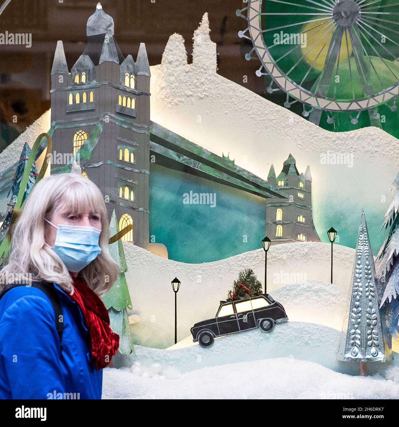 Le persone che indossano le maschere protettive Covid-19 passano davanti a una vetrina a tema natalizio su Regents Street, Londra. Foto Stock